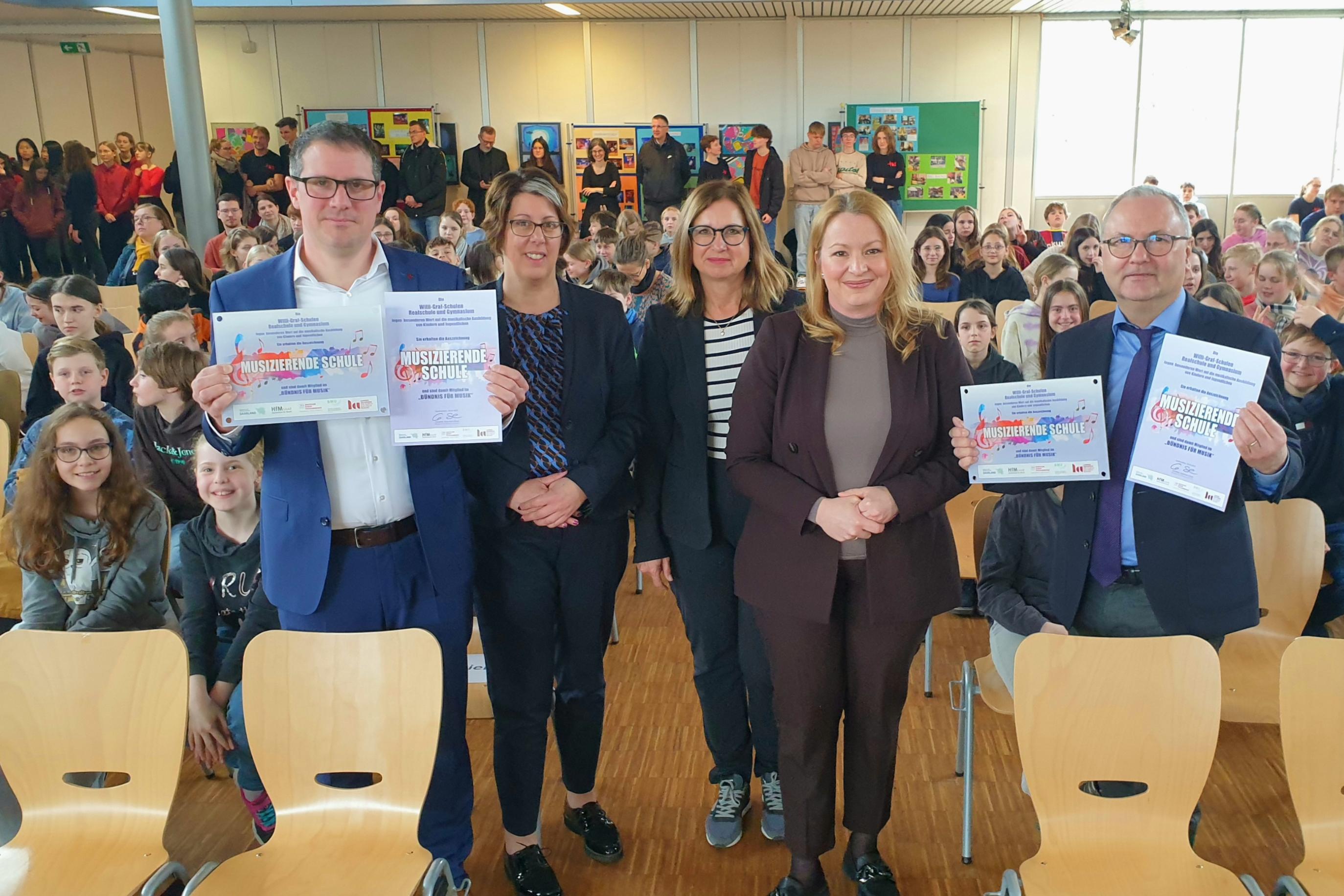 Freuten sich über die Auszeichnung der Willi-Graf-Schulen als 'Musizierende Schulen': Stephan Arnold (Schulleiter Realschule), Kerstin Schmitz (Leiterin des Arbeitsbereich Katholische Schulen im Bischöflichen Generalvikariat), Eva Kieser (Vizepräsidentin des Bundesverbandes für Musikunterricht und Projektleiterin zur Ausbildung der Musikmentoren in der Landesakademie in Ottweiler), Christine Streichert-Clivot (Ministerin für Bildung und Kultur des Saarlandes) und Stefan Kilz (Leiter des Gymnasiums)