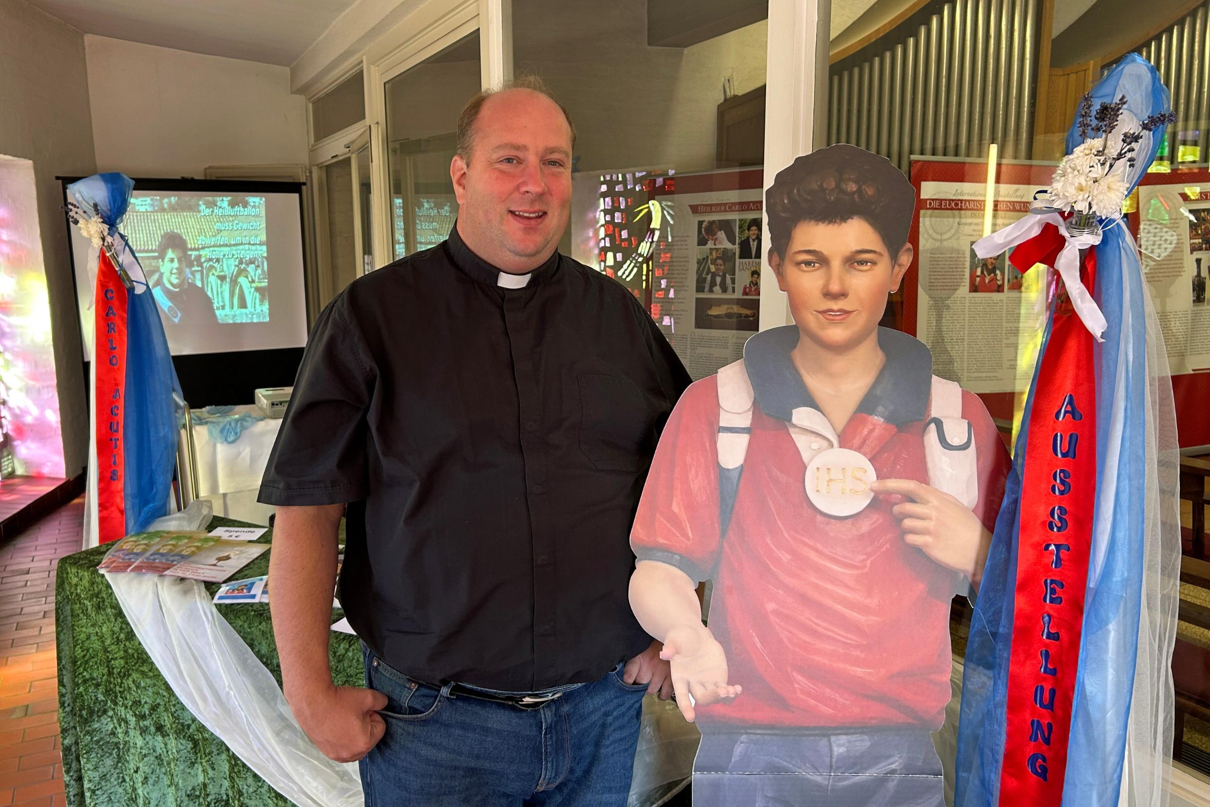 Pfarrer Lars Meiser mit einem lebensgroßen Aufsteller des Heiligen Carlo Acutis im Eingangsbereich der Klosterkirche.