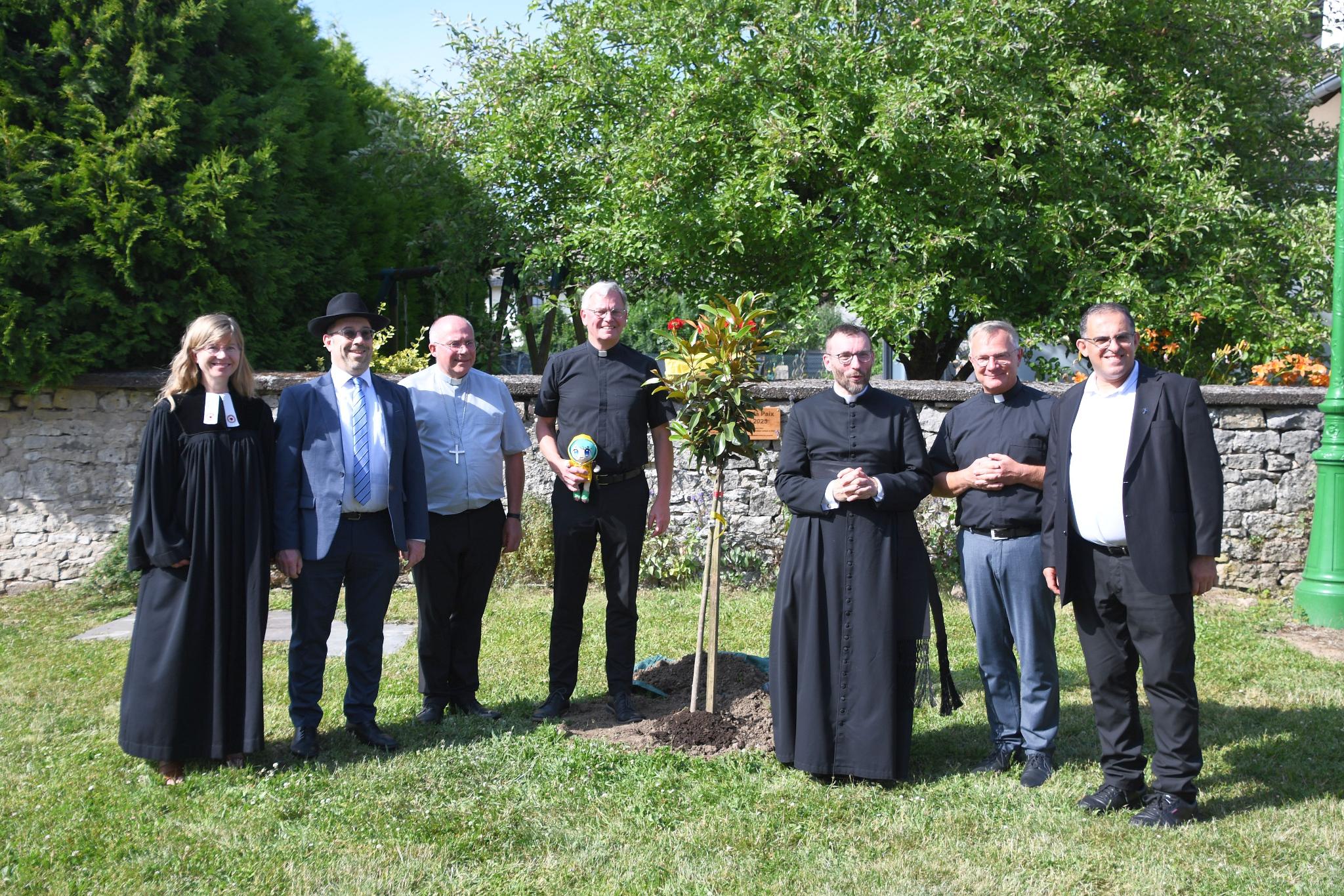 Cosima Hoffmann, Ariel Wertenschlag, Erzbischo Philippe Ballot, Generalvikar Ulrich von Plettenberg, David Chaudey, Markus Wirth und Samih Raad vor dem frisch gepflanzten Friedensbaum.