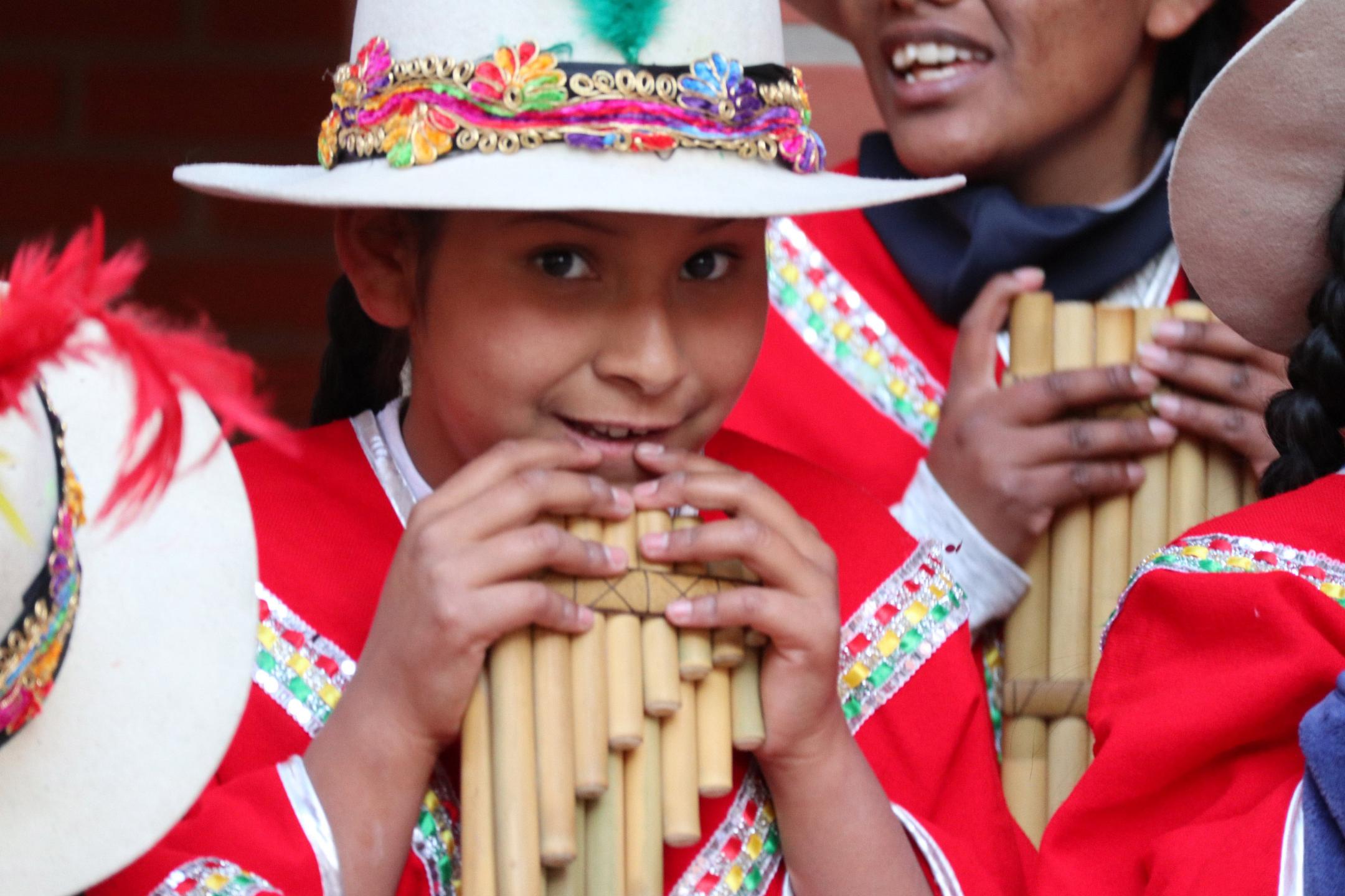 Bolivianisches Mädchen in traditioneller Tracht und mit Panflöte.